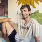 Profile photo of a man sitting on a bench in a relaxed pose smiling