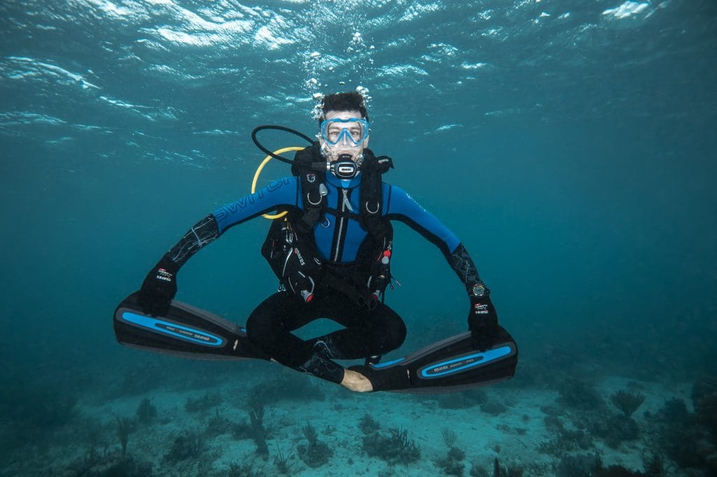 Man floating crossed leg underwater on a shallow reef