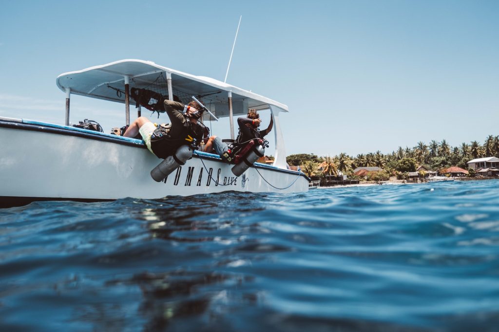 Two fun divers dropping into the water from the boat