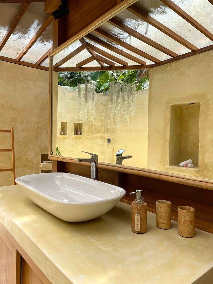 A beautiful, clean open air bathroom with a large mirror and yellow polished cement at Nusa Penida Diving's partner dive & stay accommodation
